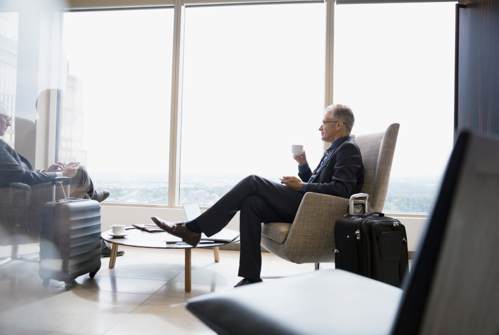 Businessman With Luggage Drinking Coffee In Airport Lounge